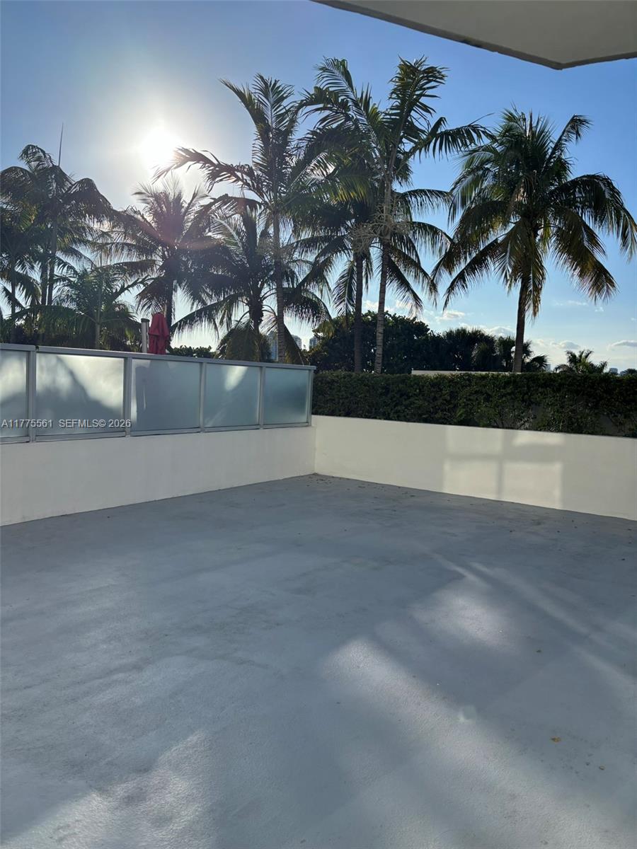 A rooftop terrace features a concrete floor, a low white wall, and glass privacy panels — 2001 Meridian Ave # 309, Miami Beach FL 33139, MIAMI BEACH, FL