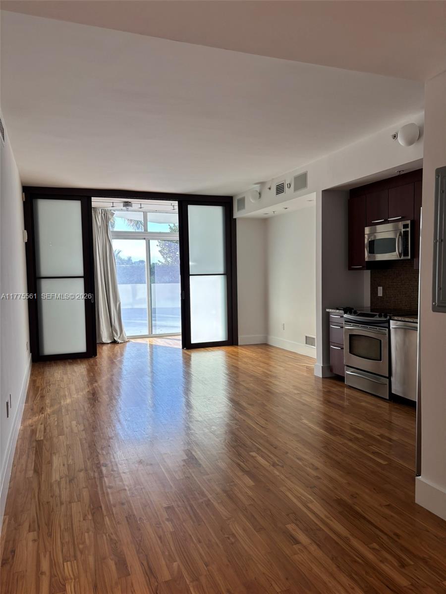 A living area with hardwood floors leads to a balcony through large sliding glass doors — 2001 Meridian Ave # 309, Miami Beach FL 33139, MIAMI BEACH, FL