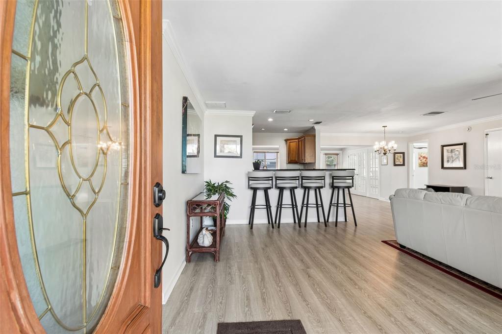 A view from an entryway into an open-concept living area with wood-look flooring and bar seating — 546 GERSHWIN DRIVE, LARGO, FL