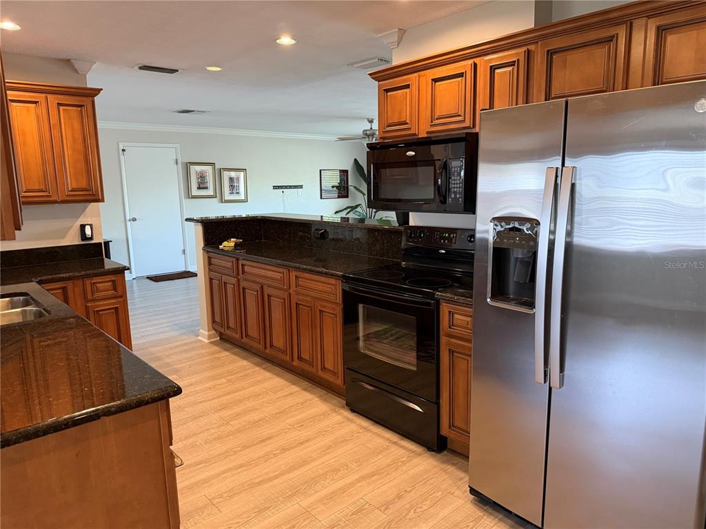 A kitchen features wood cabinets, dark granite countertops, and stainless steel appliances — 546 GERSHWIN DRIVE, LARGO, FL