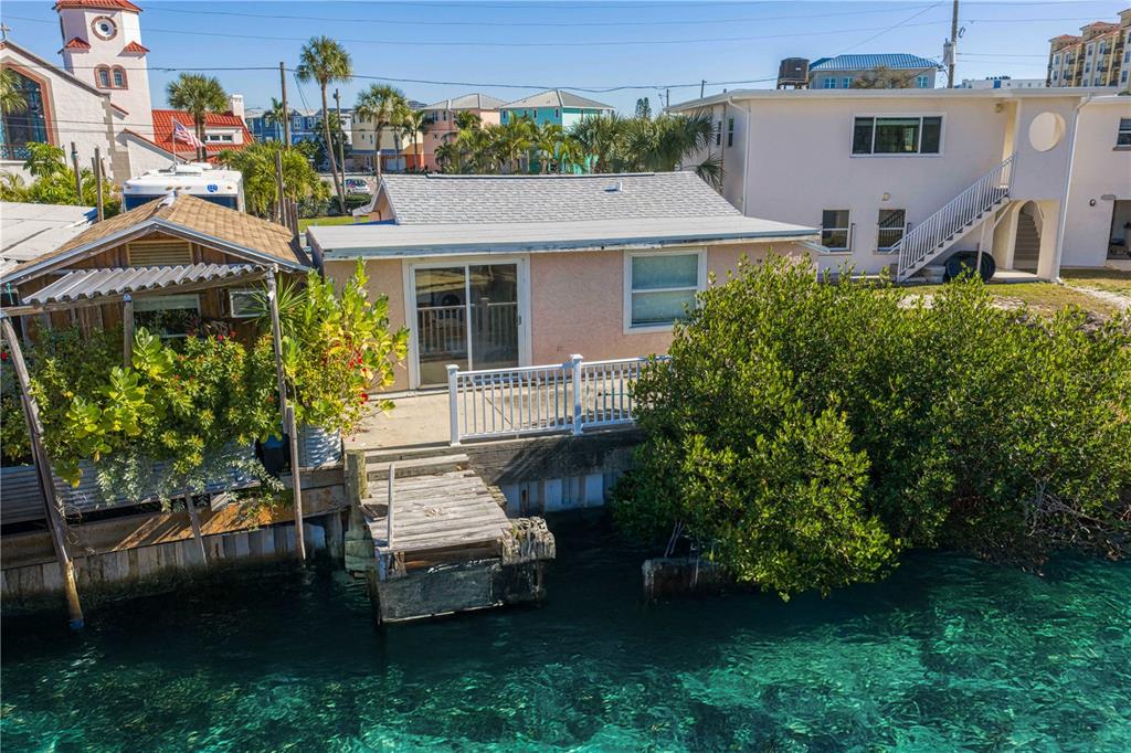 A small waterfront house with a wooden dock, patio, and white railing sits by the water — 50 137TH AVENUE CIRCLE, MADEIRA BEACH, FL