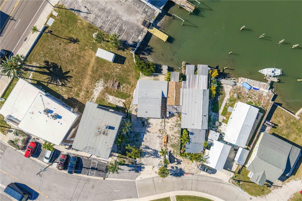 An aerial view shows several buildings, a parking area, and a boat docked in the water — 50 137TH AVENUE CIRCLE, MADEIRA BEACH, FL