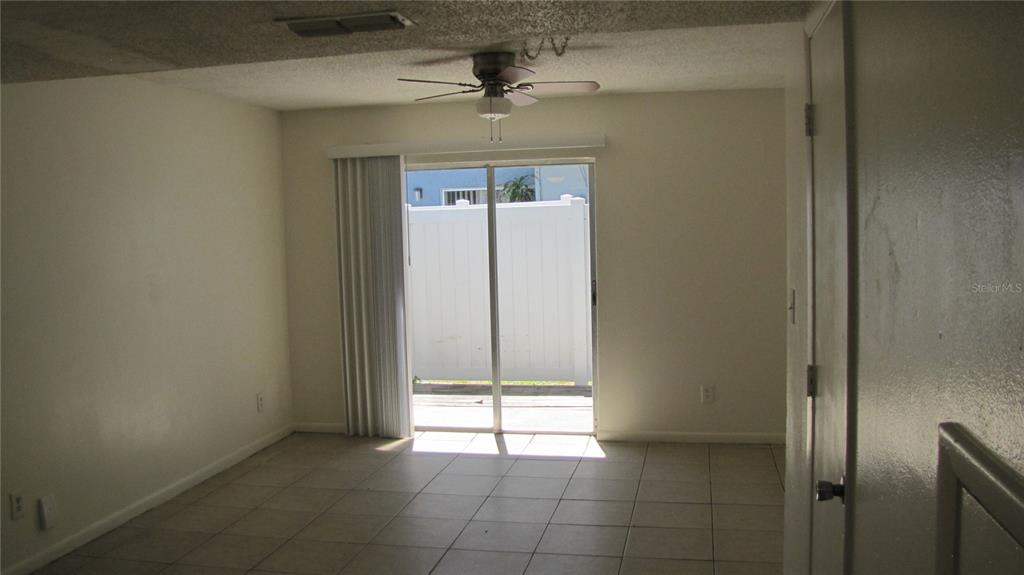 A room with light-colored tile flooring, a ceiling fan, and sliding glass doors to a patio — 5122 TEMPLE HEIGHTS ROAD UNIT C, TAMPA, FL