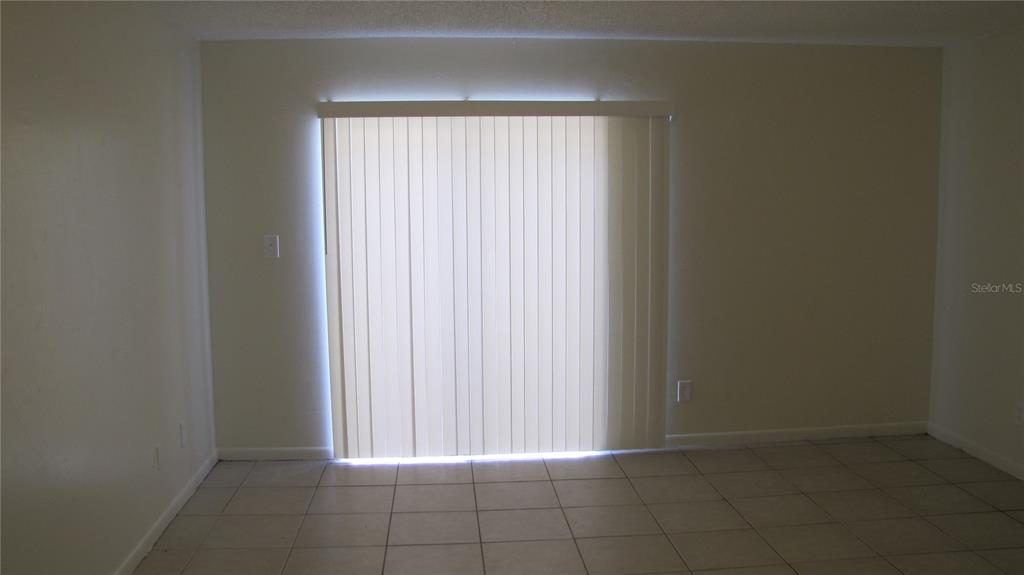 A room with light-colored walls, tiled flooring, and a sliding glass door with vertical blinds — 5122 TEMPLE HEIGHTS ROAD UNIT C, TAMPA, FL