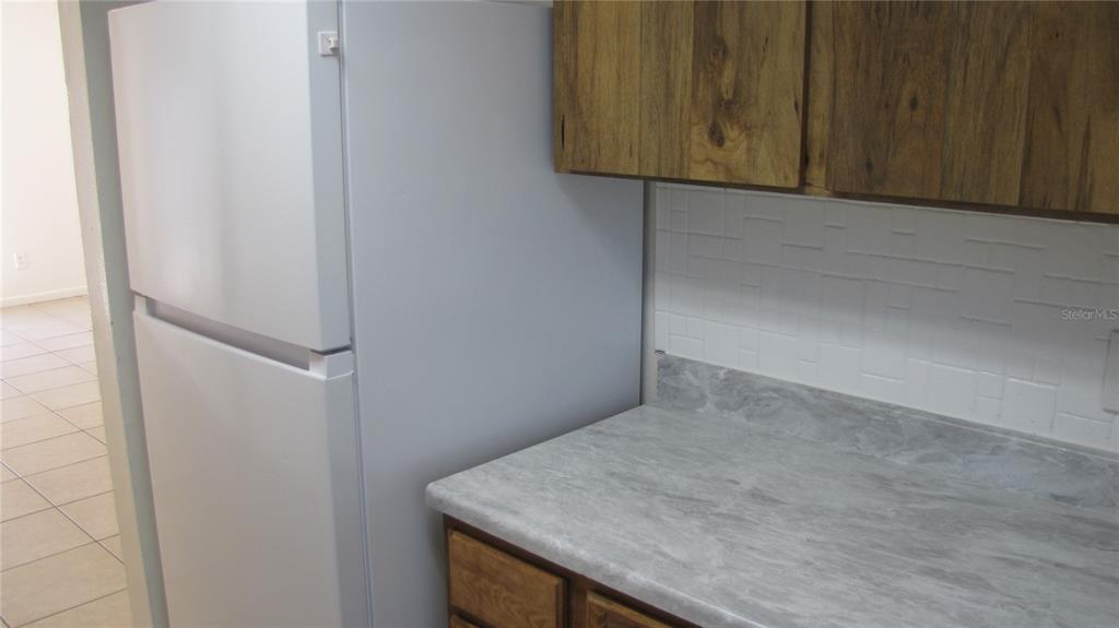 A white refrigerator stands next to a kitchen counter with a gray countertop and backsplash — 5122 TEMPLE HEIGHTS ROAD UNIT C, TAMPA, FL