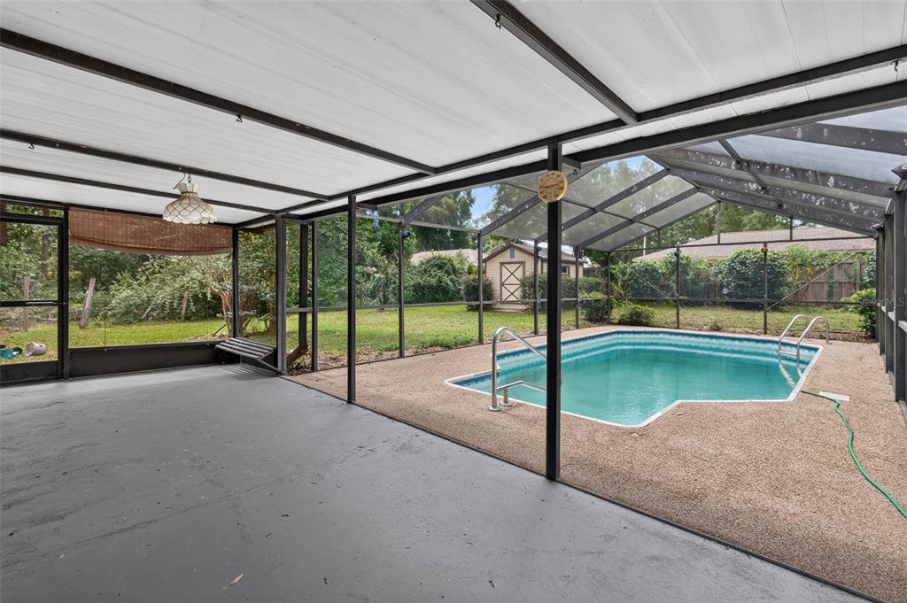 A covered patio with a concrete floor overlooks a screened-in swimming pool and backyard — 5080 E PRENTICE LANE, INVERNESS, FL