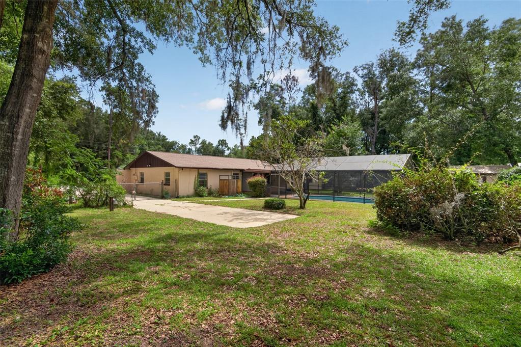 A single-story house with a screened-in pool and a concrete driveway in a wooded yard — 5080 E PRENTICE LANE, INVERNESS, FL