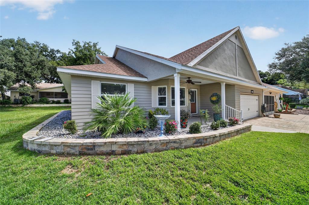 A single-story house with beige siding, a stone retaining wall, and a covered front porch — 8471 SW 91ST STREET UNIT A, OCALA, FL