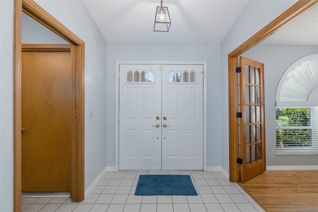 A foyer features white double doors, tiled flooring, and a wooden door on the left — 7751 LEIGHTON CIRCLE, NEW PORT RICHEY, FL