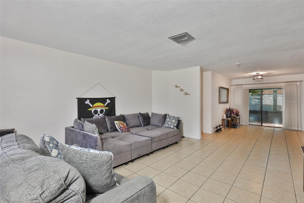 A living room with gray sectionals, tile flooring, and a One Piece flag on the wall — 5534 22ND AVENUE N, ST PETERSBURG, FL