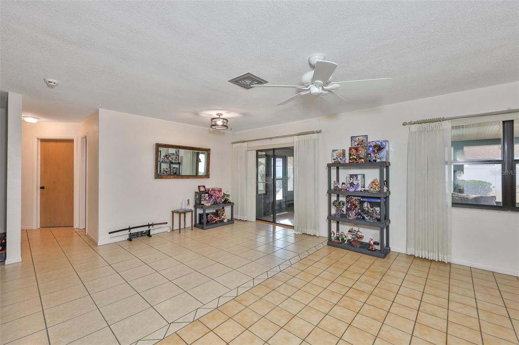 A living room with light tile floors, a ceiling fan, and a display shelf — 5534 22ND AVENUE N, ST PETERSBURG, FL