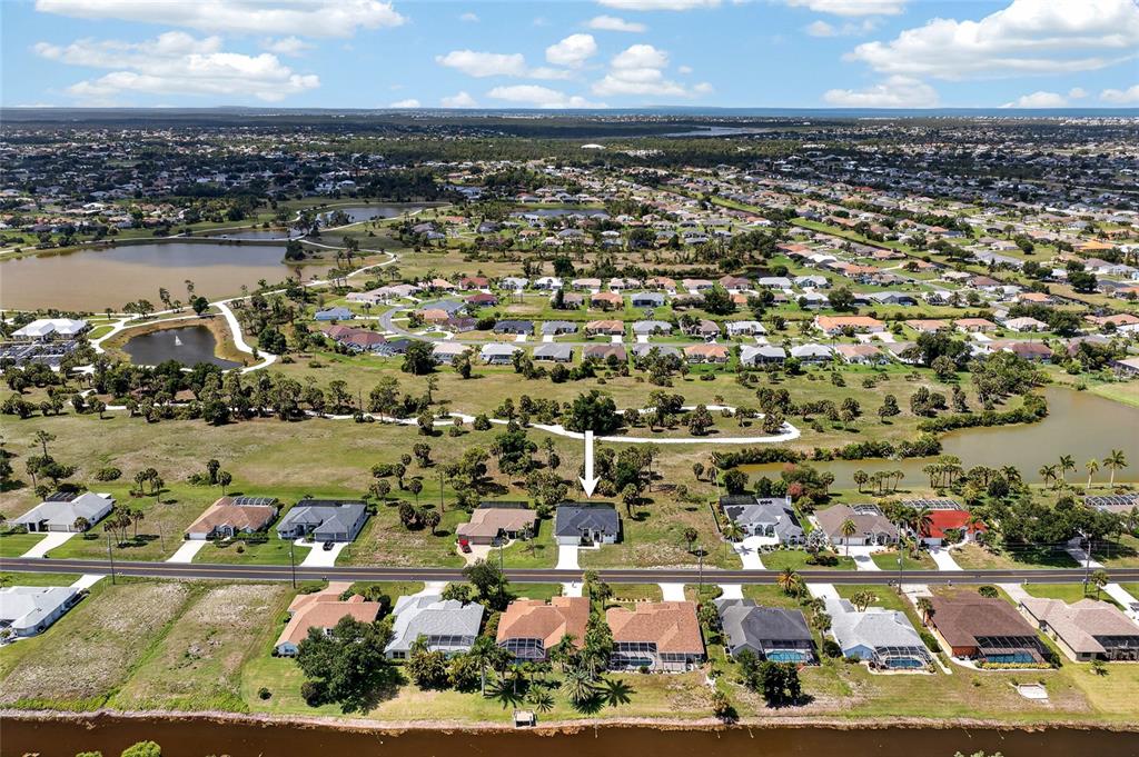 An aerial view shows a residential neighborhood with houses, a road, and nearby ponds — 592 ROTONDA CIRCLE, ROTONDA WEST, FL