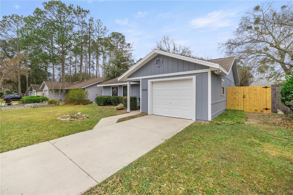 A gray single-story house with a white garage door and a concrete driveway — 3730 NW 61ST PLACE, GAINESVILLE, FL