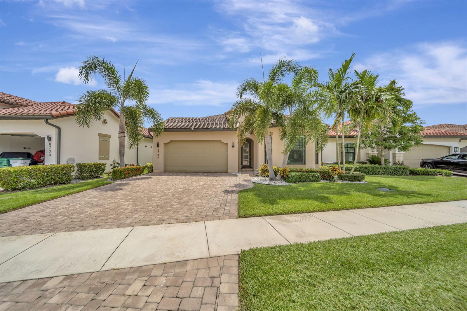 A single-story house with a tan stucco exterior, a tile roof, and a paved driveway — 8720 E Baypoint Circle, Parkland FL 33076, PARKLAND, FL