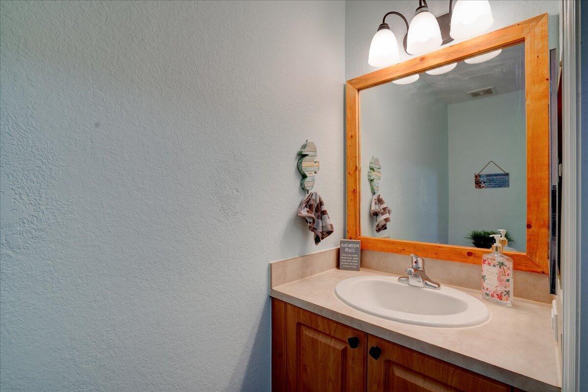 A bathroom vanity features a wooden cabinet, a beige countertop, and a framed mirror — 6633 Old Farm Trail, Boynton Beach FL 33437, BOYNTON BEACH, FL