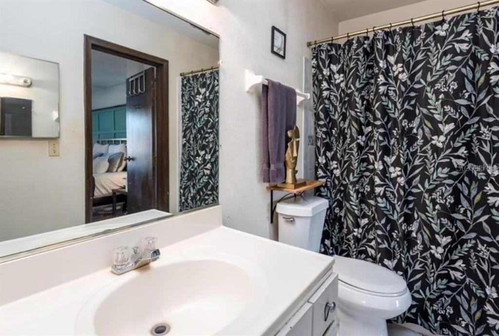 A bathroom features a white vanity, a toilet, and a black and white floral shower curtain — 2342 HUNTINGTON GREEN COURT UNIT 2, ORLANDO, FL