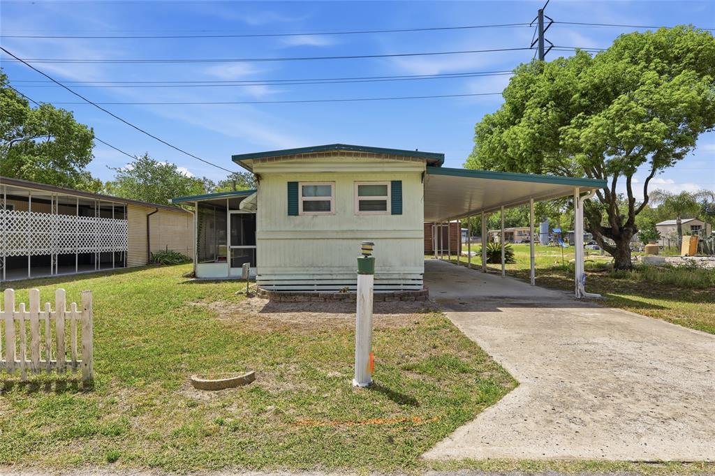 A single-story mobile home with a carport and a screened porch sits on a lawn — 37622 MARCH LANE, ZEPHYRHILLS, FL