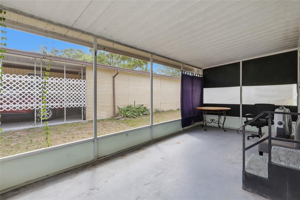 A screened-in porch with a concrete floor, metal siding, and a view of the yard — 37622 MARCH LANE, ZEPHYRHILLS, FL