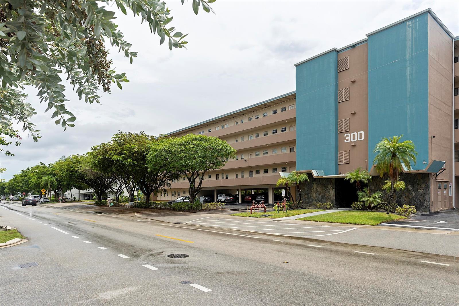 A multi-story apartment building with a blue facade and covered parking sits beside a street — 300 NE 14th Avenue # 501, FL 33009, FL