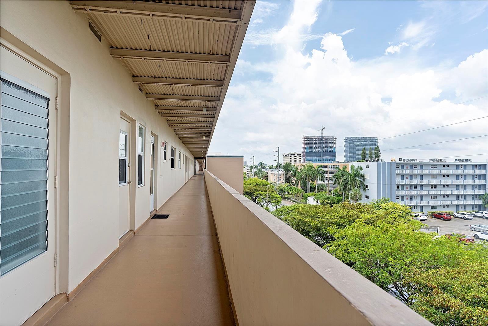 An exterior walkway with a beige floor and metal roof overlooks a city landscape — 300 NE 14th Avenue # 501, FL 33009, FL