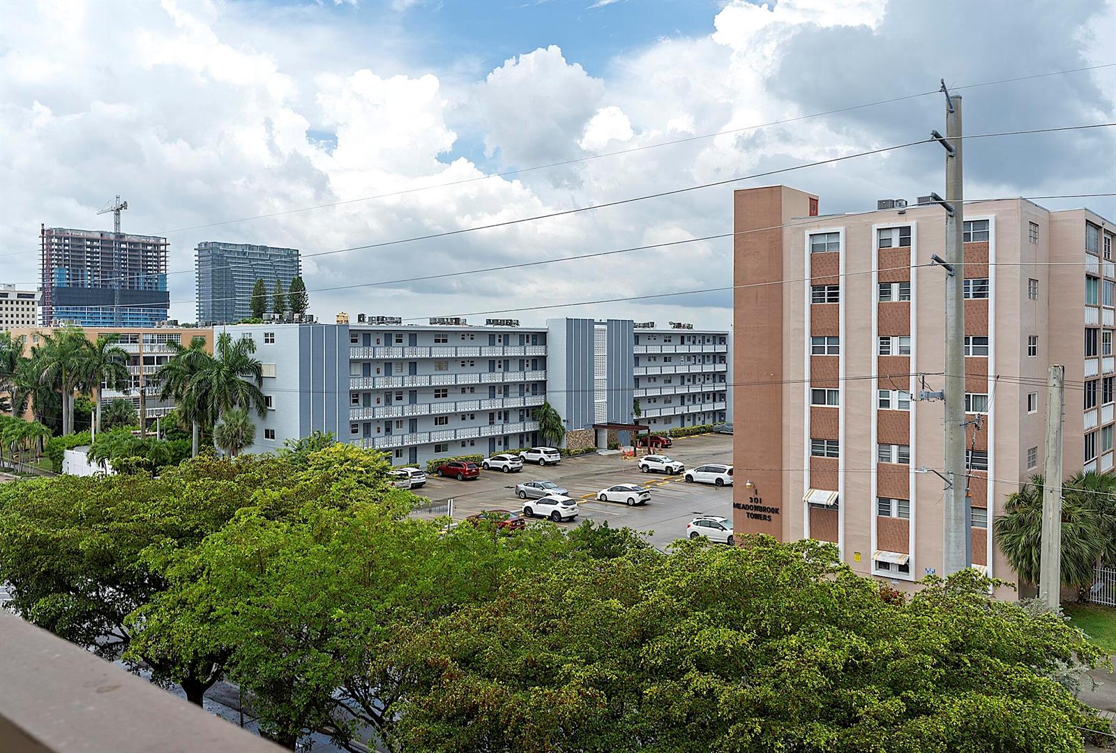 An exterior view shows two apartment buildings with a parking lot and surrounding trees — 300 NE 14th Avenue # 501, FL 33009, FL