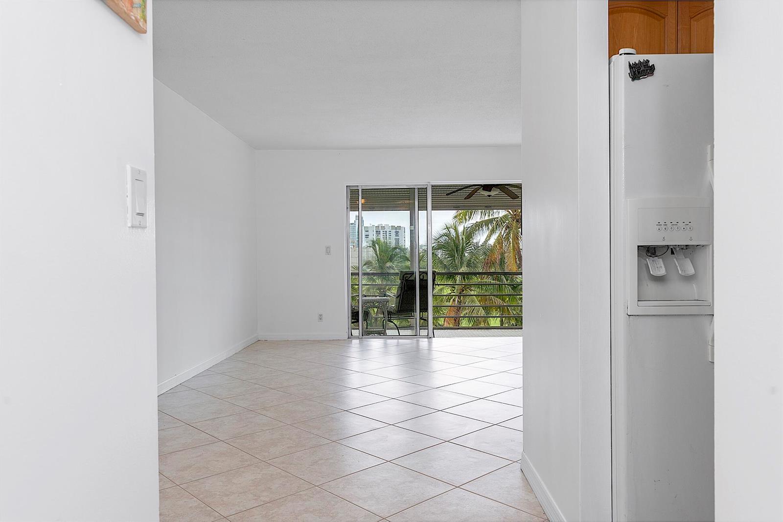 A view from a kitchen doorway looking into a living room with tile floors and balcony — 300 NE 14th Avenue # 501, FL 33009, FL