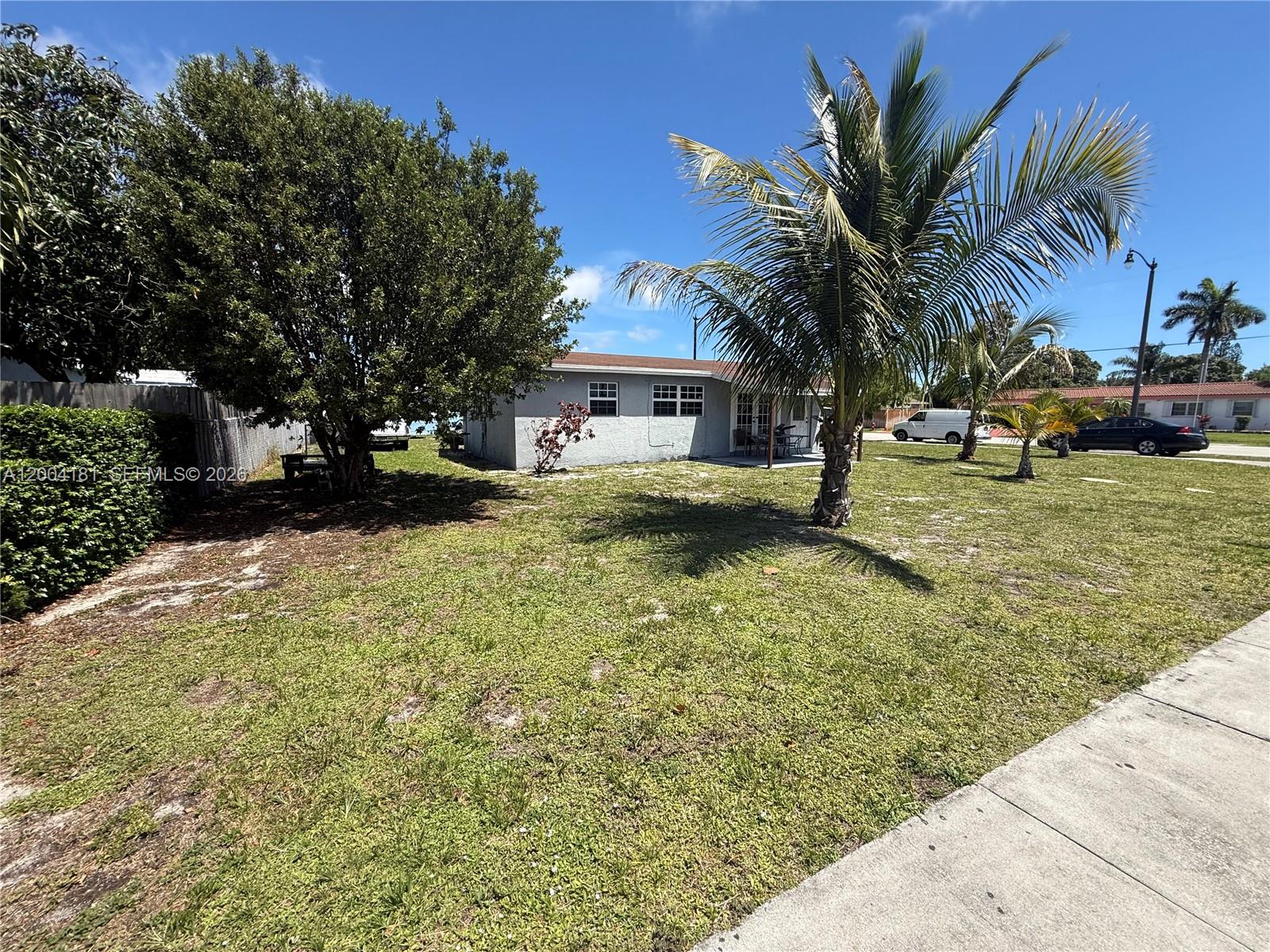 A single-story house with a yard, palm trees, and a sidewalk under a blue sky — 1701 NW 6th Ave, Pompano Beach FL 33060, POMPANO BEACH, FL