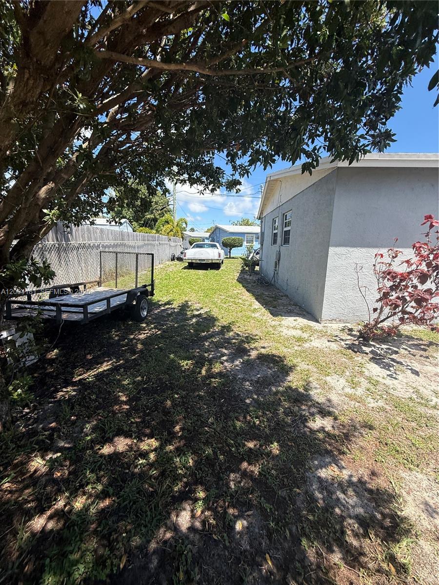 A side yard features a utility trailer, a parked car, and a house exterior — 1701 NW 6th Ave, Pompano Beach FL 33060, POMPANO BEACH, FL