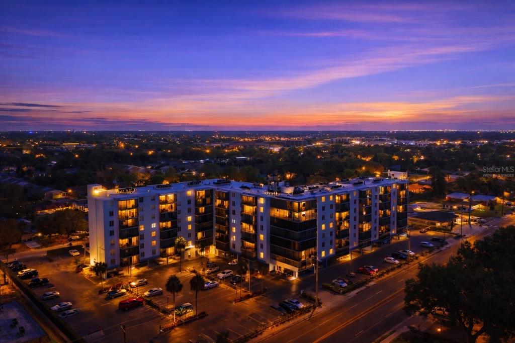 An aerial view of a multi-story apartment building at dusk with a parking lot below — 2901 26TH STREET W UNIT 509, BRADENTON, FL