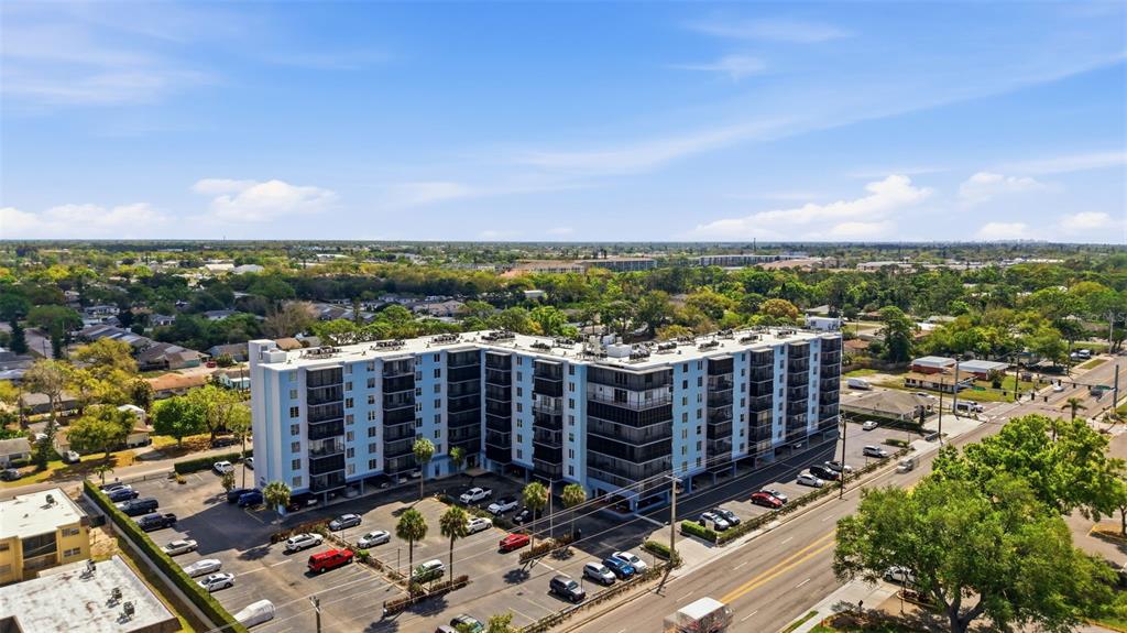 An aerial view shows a multi-story apartment building surrounded by parking lots and trees — 2901 26TH STREET W UNIT 509, BRADENTON, FL