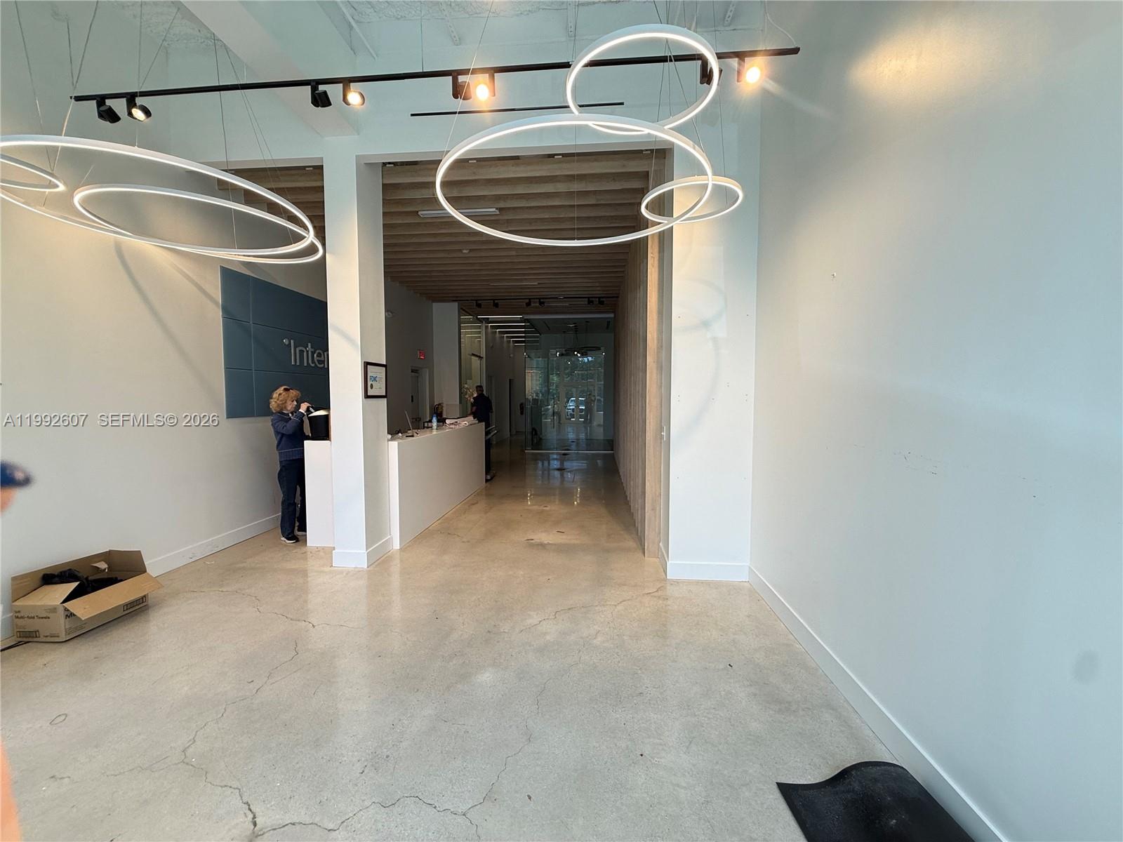 A modern office lobby features polished concrete floors, circular pendant lighting, and a reception desk — 10015 NW 41st St # 103, Doral FL 33178, DORAL, FL