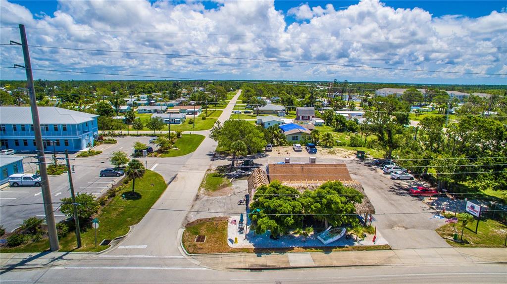 An aerial view shows a thatched-roof building, a blue multi-story structure, and surrounding neighborhood streets — 2901 PLACIDA ROAD, ENGLEWOOD, FL