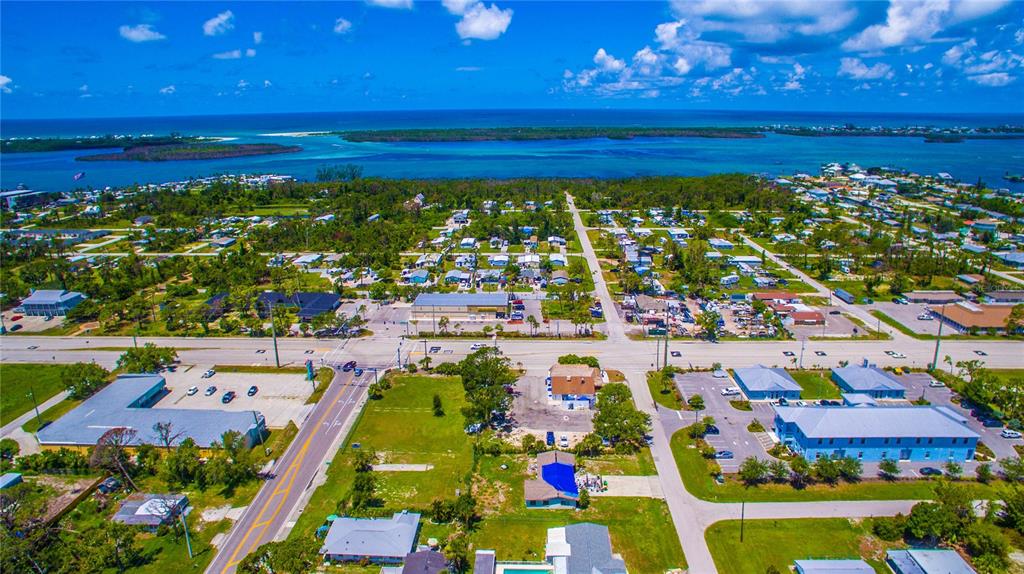An aerial view shows a coastal neighborhood with houses, commercial buildings, and roads near water — 2901 PLACIDA ROAD, ENGLEWOOD, FL