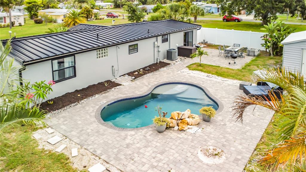 An aerial view of a backyard featuring a kidney-shaped pool, paver patio, and house exterior — 1161 KEHOSEE LANE, ENGLEWOOD, FL