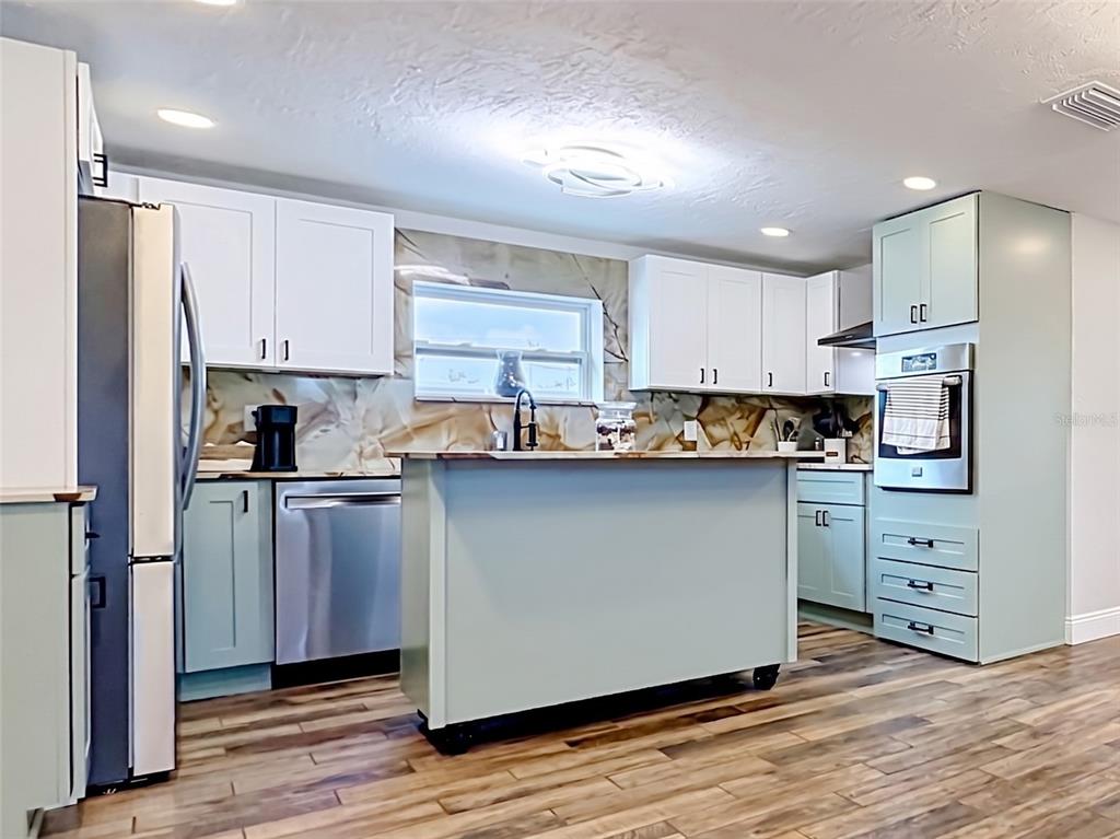 A kitchen features light blue and white cabinetry, stainless steel appliances, and a mobile island — 1161 KEHOSEE LANE, ENGLEWOOD, FL