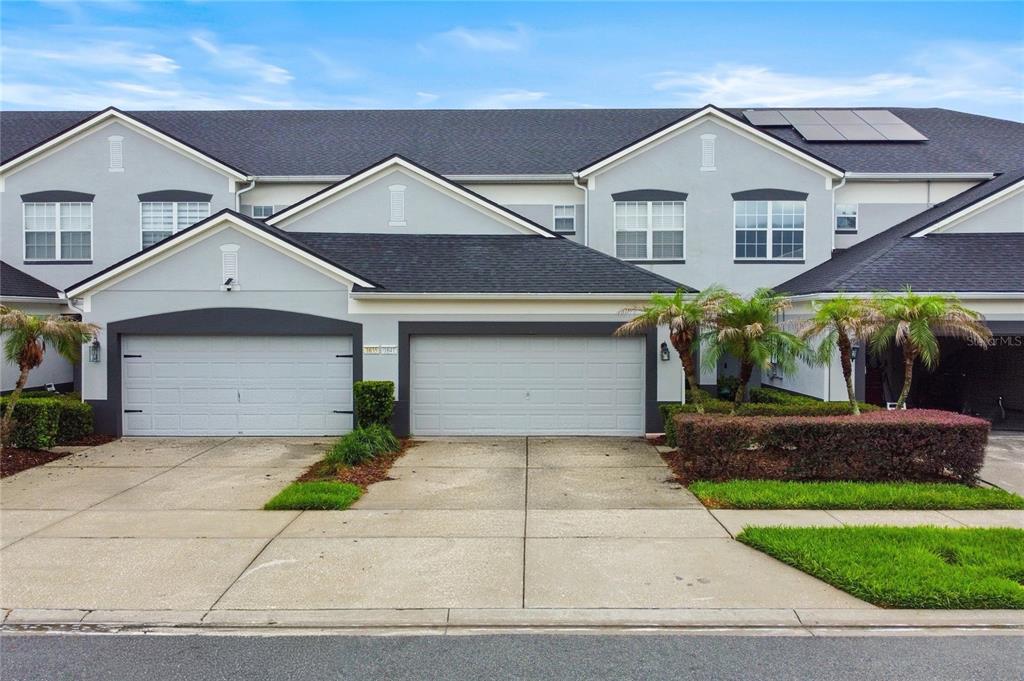 A two-story townhouse exterior features two garage doors, light gray siding, and a shingled roof — 1641 SHALLCROSS AVENUE, ORLANDO, FL