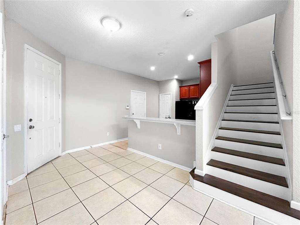 An entryway with tile flooring, a staircase, and a kitchen counter overlooking the space — 1641 SHALLCROSS AVENUE, ORLANDO, FL