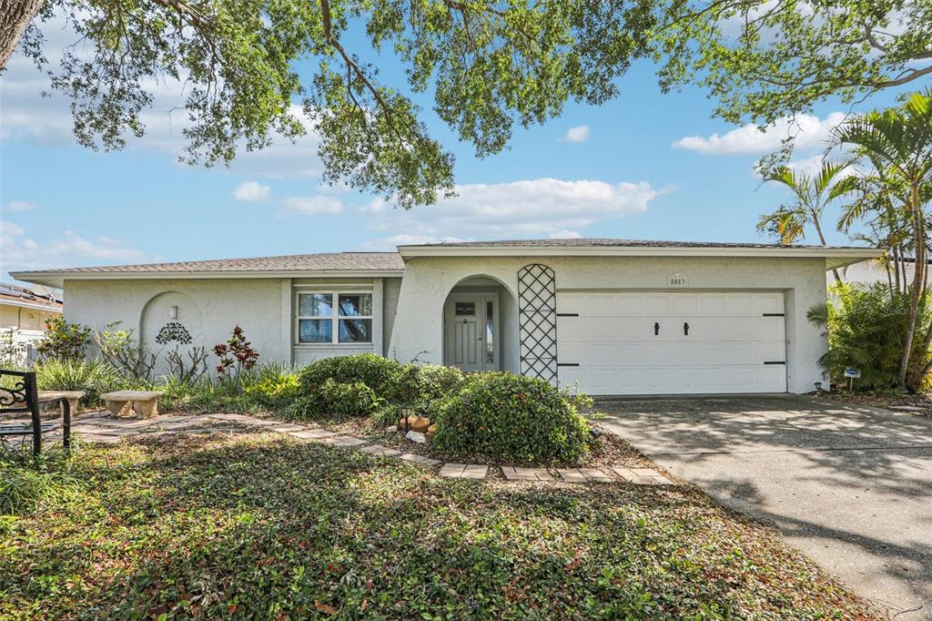 A single-story house with a white stucco exterior, a two-car garage, and a landscaped yard — 8083 BAYHAVEN DRIVE, SEMINOLE, FL