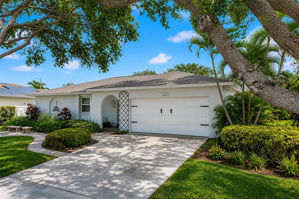 A single-story white house with a two-car garage, arched entryway, and mature landscaping — 8083 BAYHAVEN DRIVE, SEMINOLE, FL