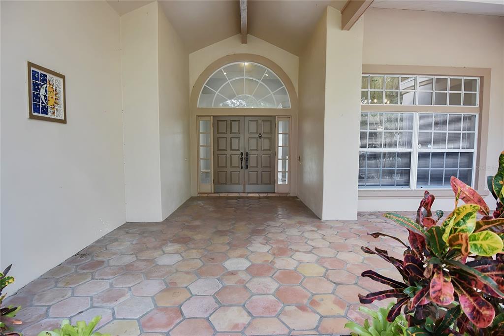 A covered entryway features a hexagonal tile floor, double front doors, and an arched transom — 4763 BRAYTON TERRACE N, PALM HARBOR, FL