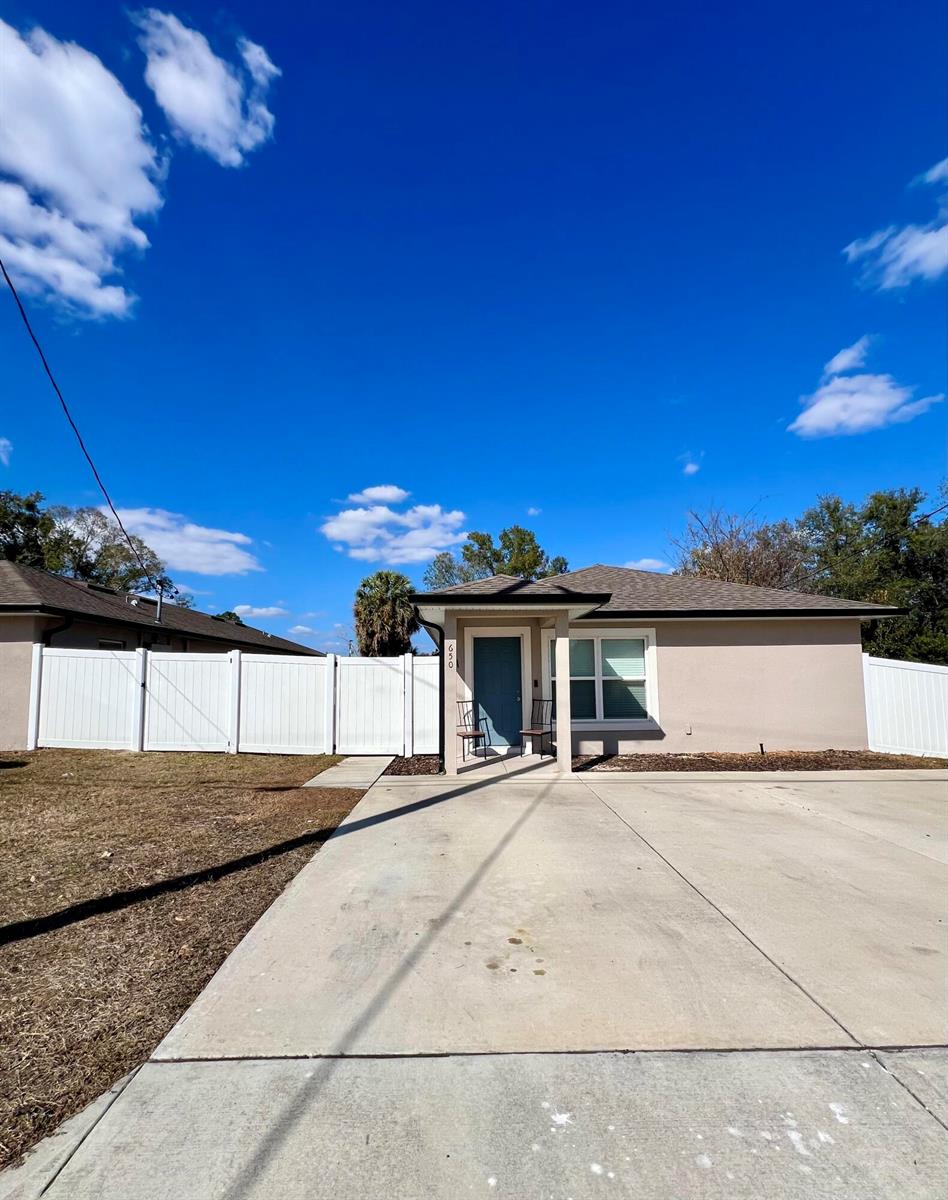 A single-story house with a beige exterior, a blue front door, and a white fence — 650 E Grapefruit Avenue # A, FL 33850, FL