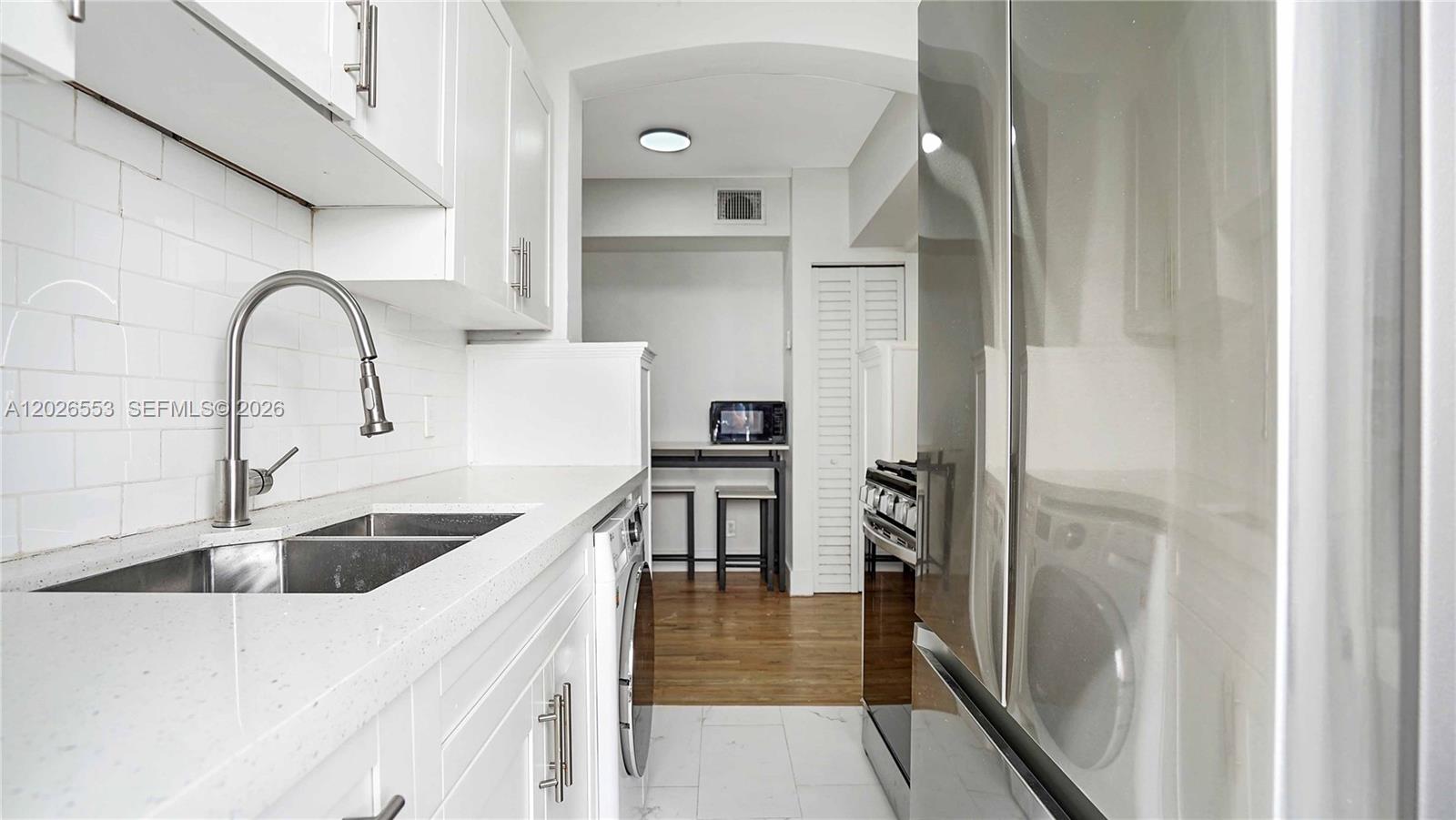 A modern kitchen features white cabinets, a stainless steel sink, and a stainless steel refrigerator — 815 W 39, Miami Beach FL 33140, MIAMI BEACH, FL