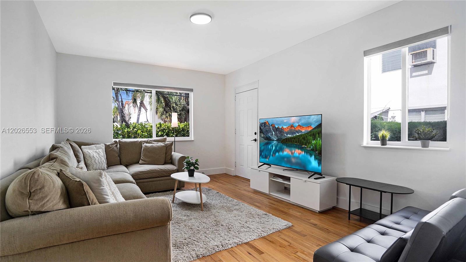 A living room features a sectional sofa, a television on a stand, and hardwood floors — 815 W 39, Miami Beach FL 33140, MIAMI BEACH, FL