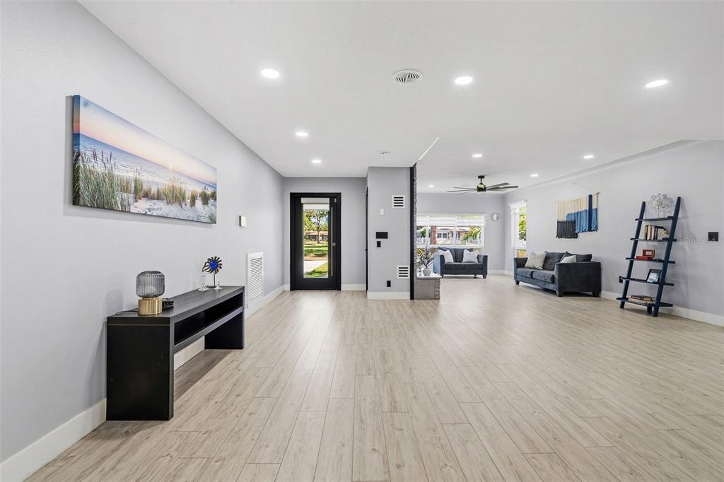 A spacious living area features light wood-look flooring, recessed lighting, and a black front door — 6228 7TH AVENUE N, ST PETERSBURG, FL