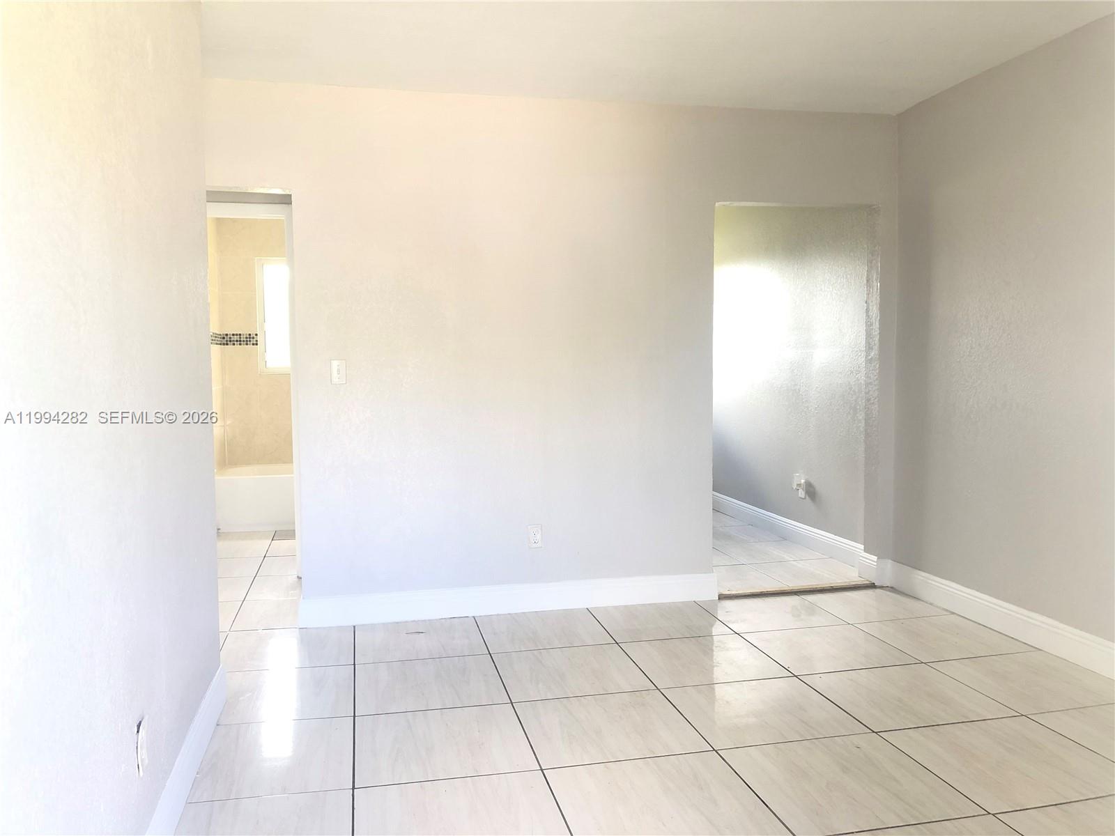 A room with light-colored tile flooring features two doorways leading to other interior spaces — 1940 Washington Ave # 11, Opa-Locka FL 33054, OPA-LOCKA, FL