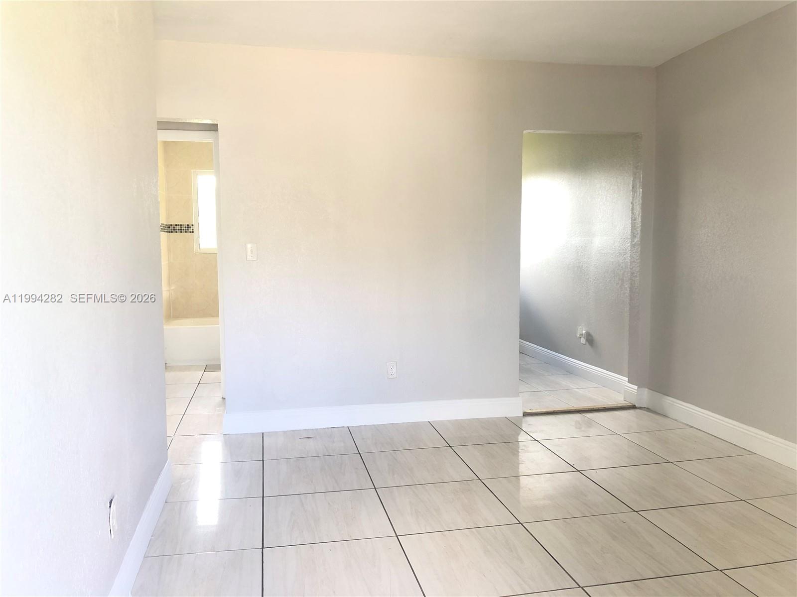 A room with light-colored tile flooring, white walls, and two doorways leading to other areas — 1940 Washington Ave # 11, Opa-Locka FL 33054, OPA-LOCKA, FL