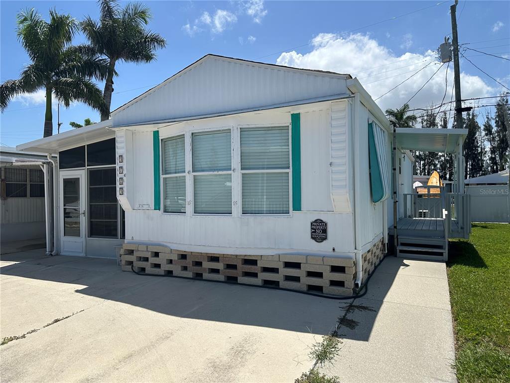 A white mobile home with a concrete driveway, palm tree, and a small wooden porch — 3723 116TH STREET W, BRADENTON, FL