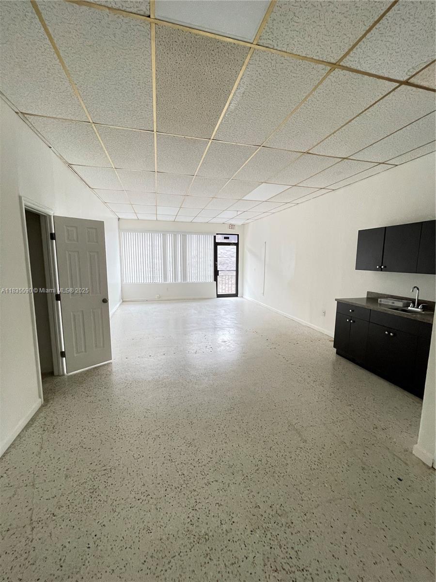 An empty office space features a drop ceiling, speckled flooring, and a small kitchenette — 1756 SW 8th St # 204, Miami FL 33135, MIAMI, FL