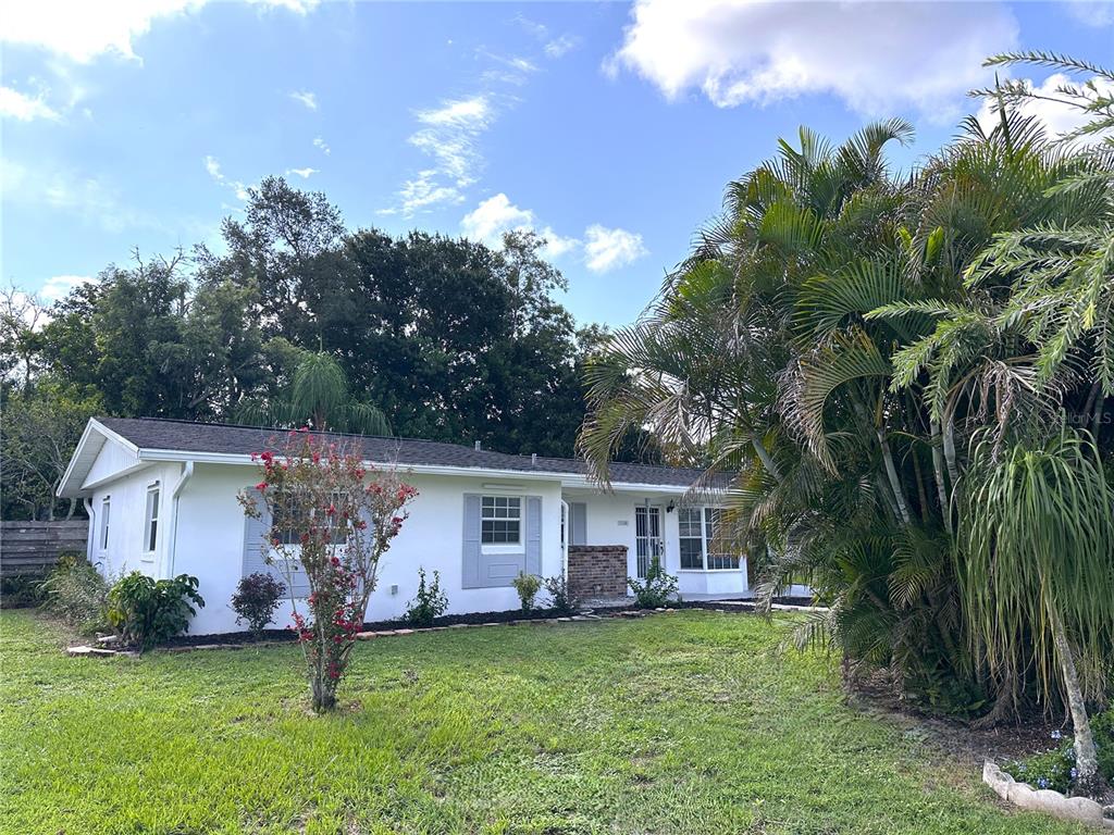 A white house exterior features a brick accent wall, a palm tree, and a bay window — 2740 HEATHER PLACE, SARASOTA, FL