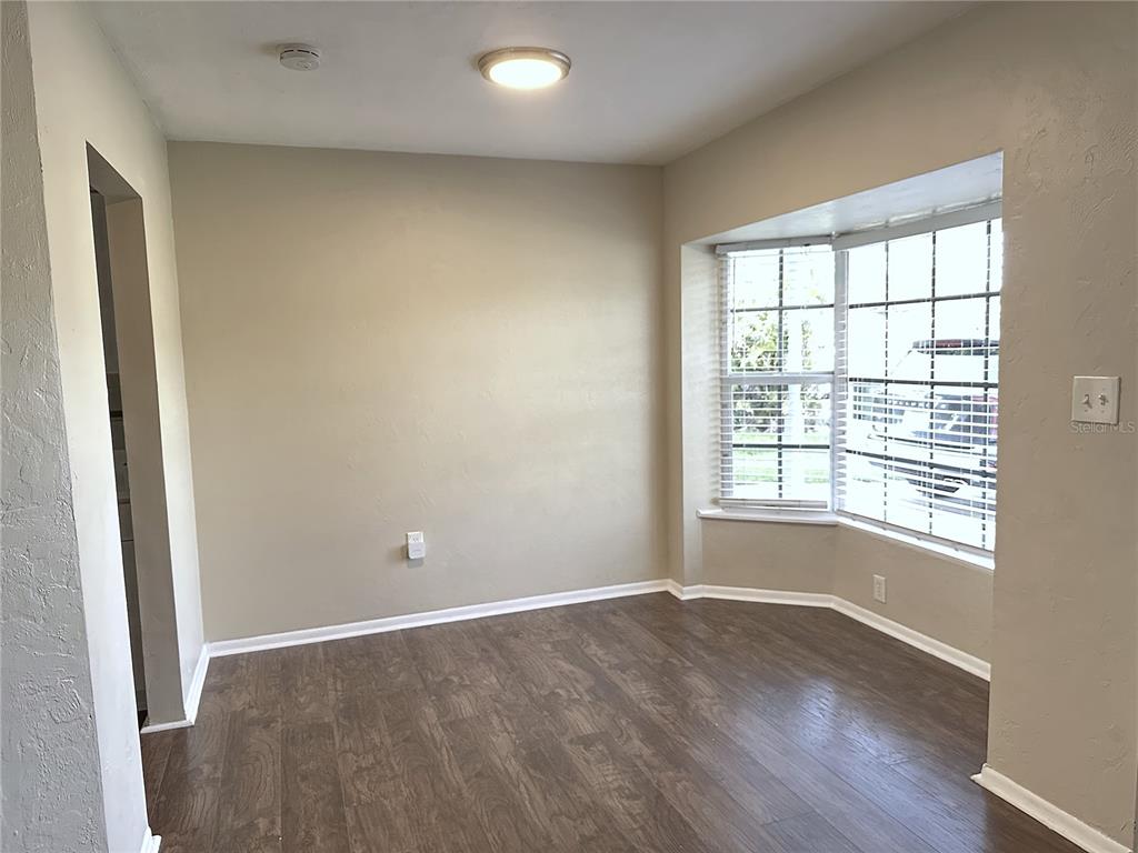 A dining room features a round wooden table, four burgundy chairs, and a bay window — 2740 HEATHER PLACE, SARASOTA, FL
